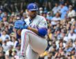 Texas Rangers pitcher Kumar Rocker lifts his front leg in his windup in a gray road uniform at American Family Field.