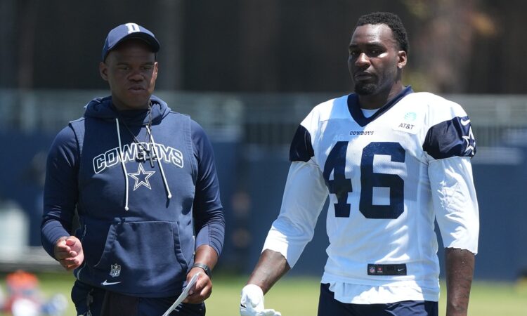 Dallas Cowboys tight ends coach Lunda Wells walks the practice field alongside tight end Michael Trigg in a No. 46 jersey.