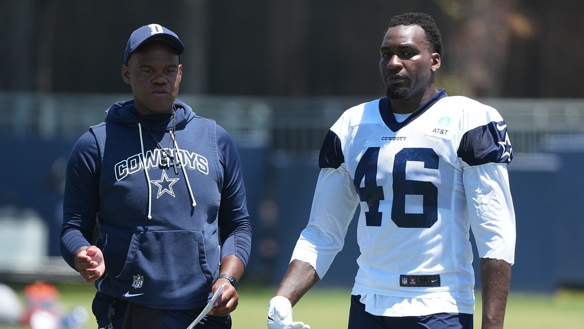 Dallas Cowboys tight ends coach Lunda Wells walks the practice field alongside tight end Michael Trigg in a No. 46 jersey.