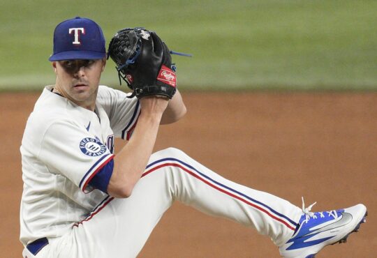 Texas Rangers pitcher MacKenzie Gore lifts his leg into the windup with his glove raised on the mound.