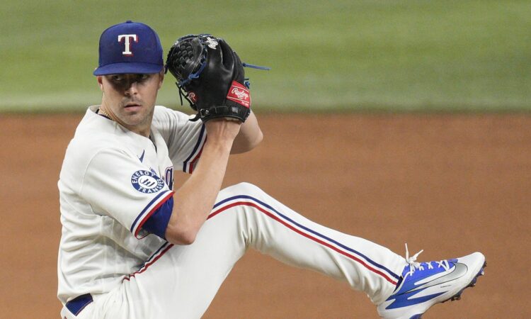 Texas Rangers pitcher MacKenzie Gore lifts his leg into the windup with his glove raised on the mound.