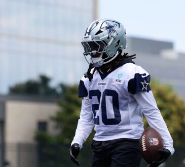 Dallas Cowboys running back Malik Davis carries a football in his left hand during a minicamp drill in his No. 20 practice jersey.