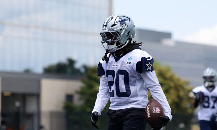 Dallas Cowboys running back Malik Davis carries a football in his left hand during a minicamp drill in his No. 20 practice jersey.