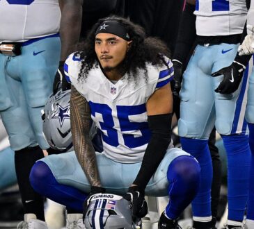 Dallas Cowboys linebacker Marist Liufau crouches on the sideline with his helmet on the turf in front of him.