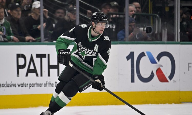 Dallas Stars defenseman Miro Heiskanen carries the puck up ice in a black home sweater during a playoff game.