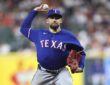 Texas Rangers starting pitcher Nathan Eovaldi rears back to deliver a pitch in a blue road jersey.