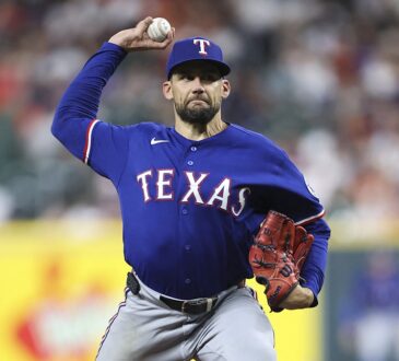 Texas Rangers starting pitcher Nathan Eovaldi rears back to deliver a pitch in a blue road jersey.
