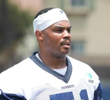 Dallas Cowboys guard Nick Leverett looks toward the field in a white No. 51 practice jersey and skullcap.
