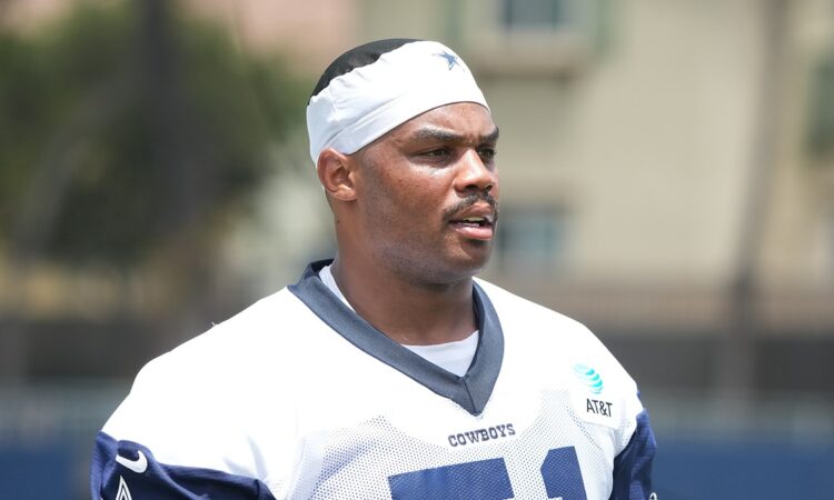 Dallas Cowboys guard Nick Leverett looks toward the field in a white No. 51 practice jersey and skullcap.