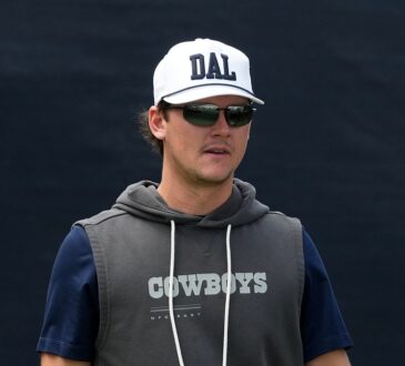 Dallas Cowboys special teams coordinator Nick Sorensen watches practice in a white DAL cap and sunglasses.