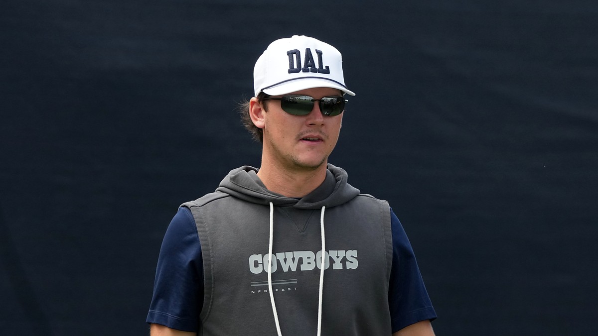 Dallas Cowboys special teams coordinator Nick Sorensen watches practice in a white DAL cap and sunglasses.