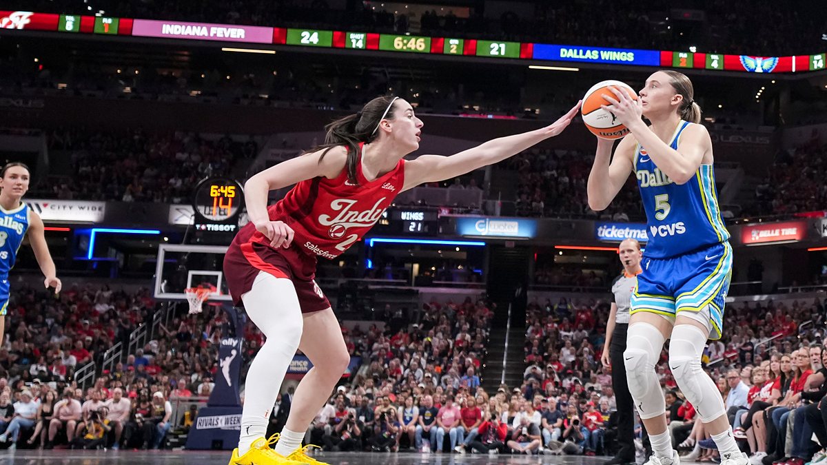 Dallas Wings guard Paige Bueckers rises to shoot as Indiana Fever guard Caitlin Clark contests with an outstretched hand.