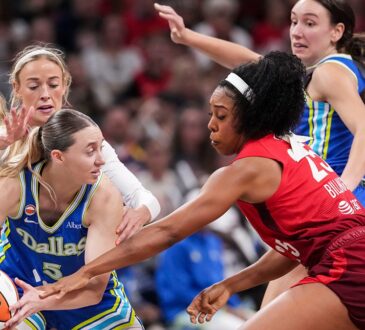 Dallas Wings guard Paige Bueckers protects the ball as two Indiana Fever defenders converge on her.