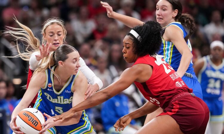 Dallas Wings guard Paige Bueckers protects the ball as two Indiana Fever defenders converge on her.