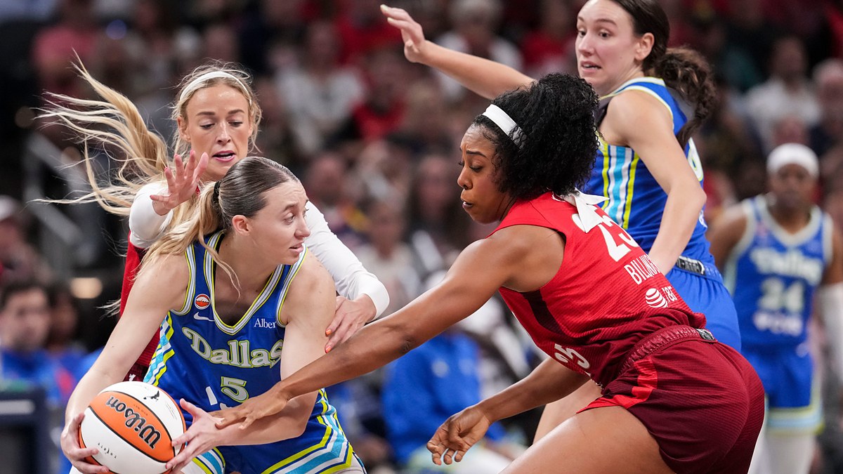 Dallas Wings guard Paige Bueckers protects the ball as two Indiana Fever defenders converge on her.
