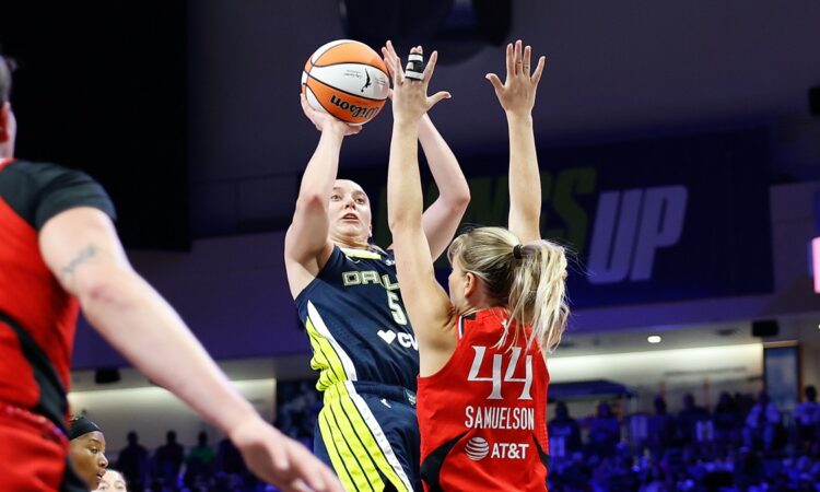 Dallas Wings guard Paige Bueckers rises for a jump shot over the outstretched arms of Portland Fire guard Karlie Samuelson.