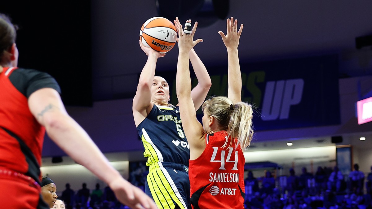 Dallas Wings guard Paige Bueckers rises for a jump shot over the outstretched arms of Portland Fire guard Karlie Samuelson.