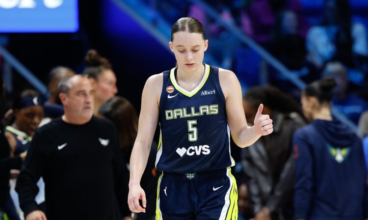 Dallas Wings guard Paige Bueckers gives a thumbs up while walking upcourt in her No. 5 jersey.