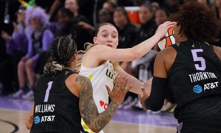 Dallas Wings guard Paige Bueckers looks for an outlet while trapped between two Golden State Valkyries defenders.