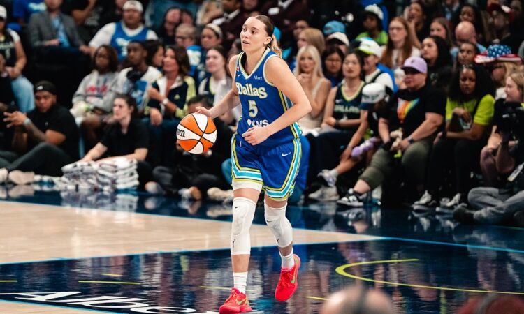 Dallas Wings guard Paige Bueckers dribbles up the floor in a blue Dallas jersey during a game.