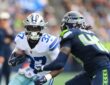 Dallas Cowboys running back Phil Mafah tucks the ball and cuts upfield as a Seattle Seahawks defender closes in.