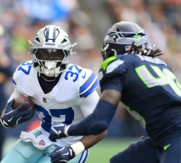 Dallas Cowboys running back Phil Mafah tucks the ball and cuts upfield as a Seattle Seahawks defender closes in.