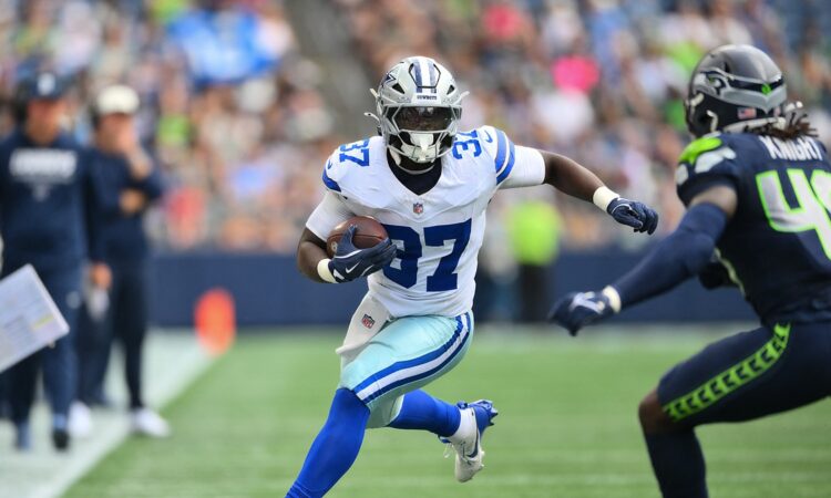 Dallas Cowboys running back Phil Mafah cuts upfield with the ball after a catch as a Seattle Seahawks defender closes in.
