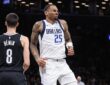 Dallas Mavericks forward P.J. Washington grimaces after an injury as Brooklyn Nets guard Egor Dëmin looks on.