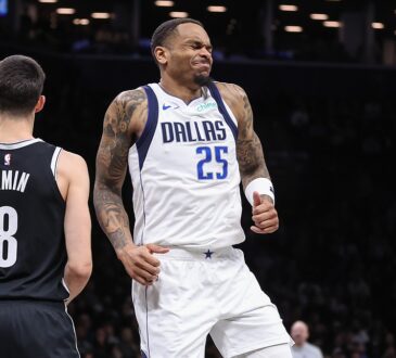 Dallas Mavericks forward P.J. Washington grimaces after an injury as Brooklyn Nets guard Egor Dëmin looks on.