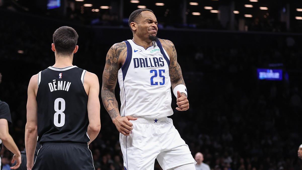 Dallas Mavericks forward P.J. Washington grimaces after an injury as Brooklyn Nets guard Egor Dëmin looks on.