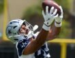 Dallas Cowboys tight end Princeton Fant reaches overhead with both hands to catch a football at training camp.