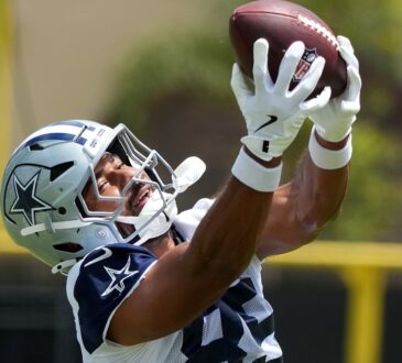 Dallas Cowboys tight end Princeton Fant reaches overhead with both hands to catch a football at training camp.