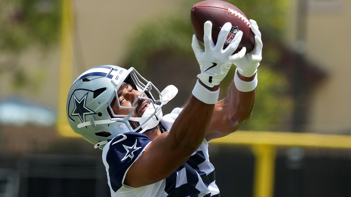 Dallas Cowboys tight end Princeton Fant reaches overhead with both hands to catch a football at training camp.