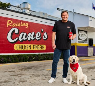 Raising Cane's founder Todd Graves stands with a yellow Labrador outside the original Raising Cane's restaurant.