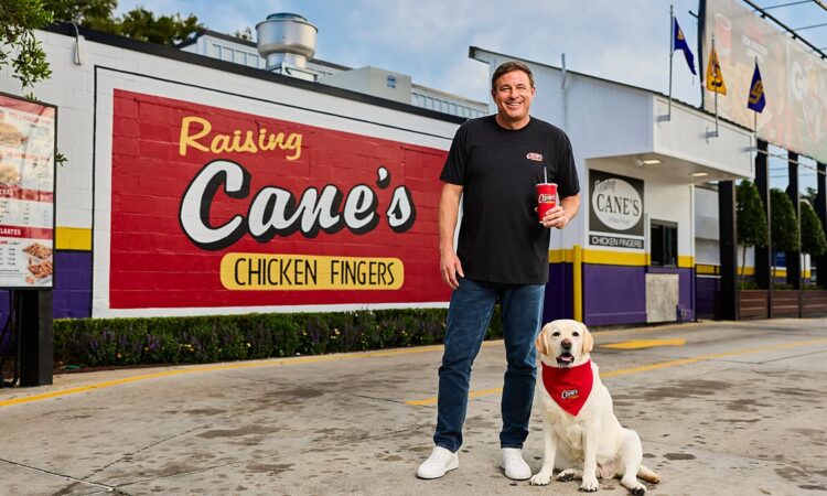 Raising Cane's founder Todd Graves stands with a yellow Labrador outside the original Raising Cane's restaurant.