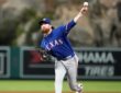 A Texas Rangers relief pitcher throws from the mound in a gray road uniform at Angel Stadium.