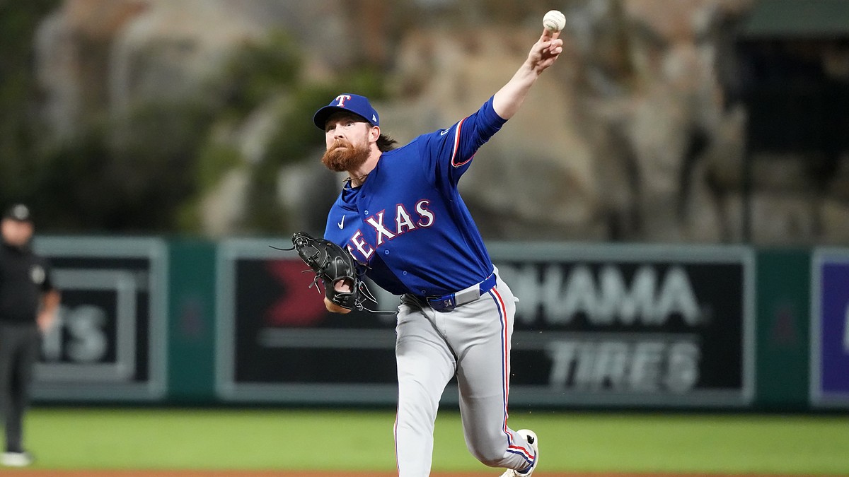 A Texas Rangers relief pitcher throws from the mound in a gray road uniform at Angel Stadium.