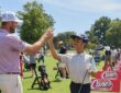 PGA Tour golfer Sam Burns clasps hands with a young golfer on the range at a First Tee and Boys and Girls Clubs event.