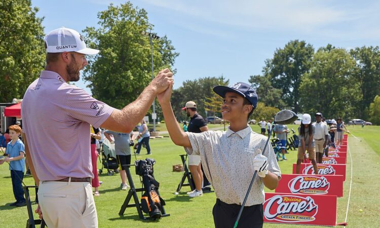 PGA Tour golfer Sam Burns clasps hands with a young golfer on the range at a First Tee and Boys and Girls Clubs event.