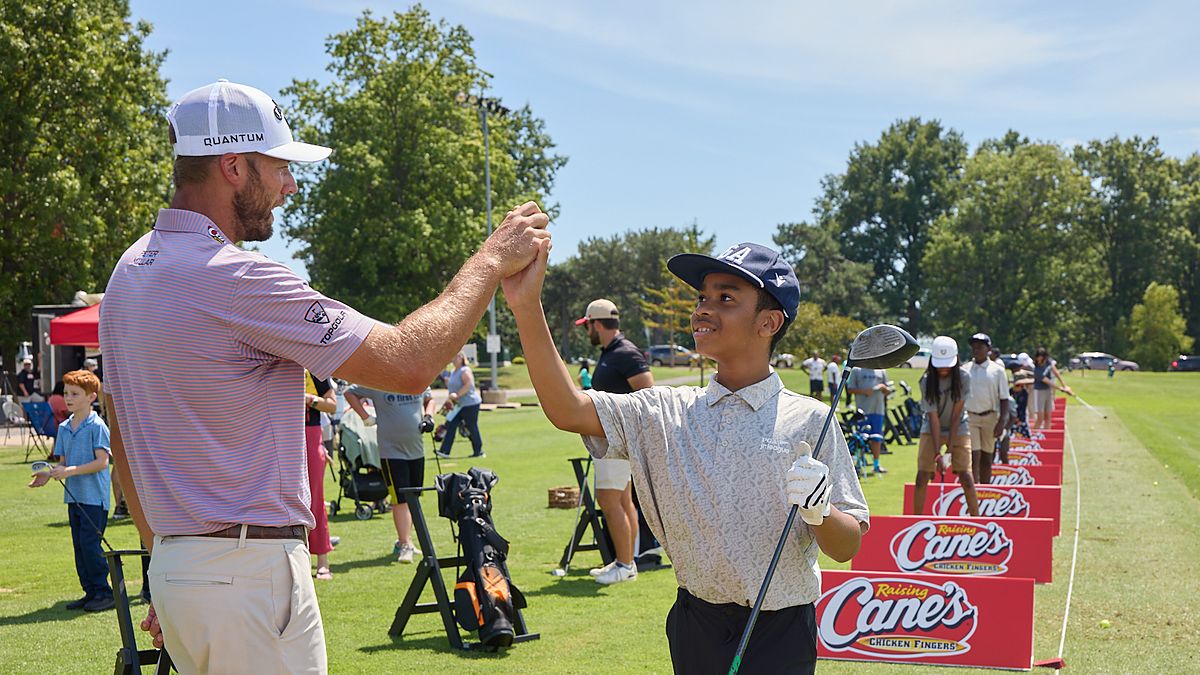 PGA Tour golfer Sam Burns clasps hands with a young golfer on the range at a First Tee and Boys and Girls Clubs event.