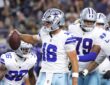 Dallas Cowboys quarterback Sam Howell holds up the ball to celebrate a two-point conversion as teammates gather behind him.