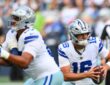 Dallas Cowboys quarterback Sam Howell holds the ball and scans downfield as a lineman blocks a Seattle Seahawks defender.