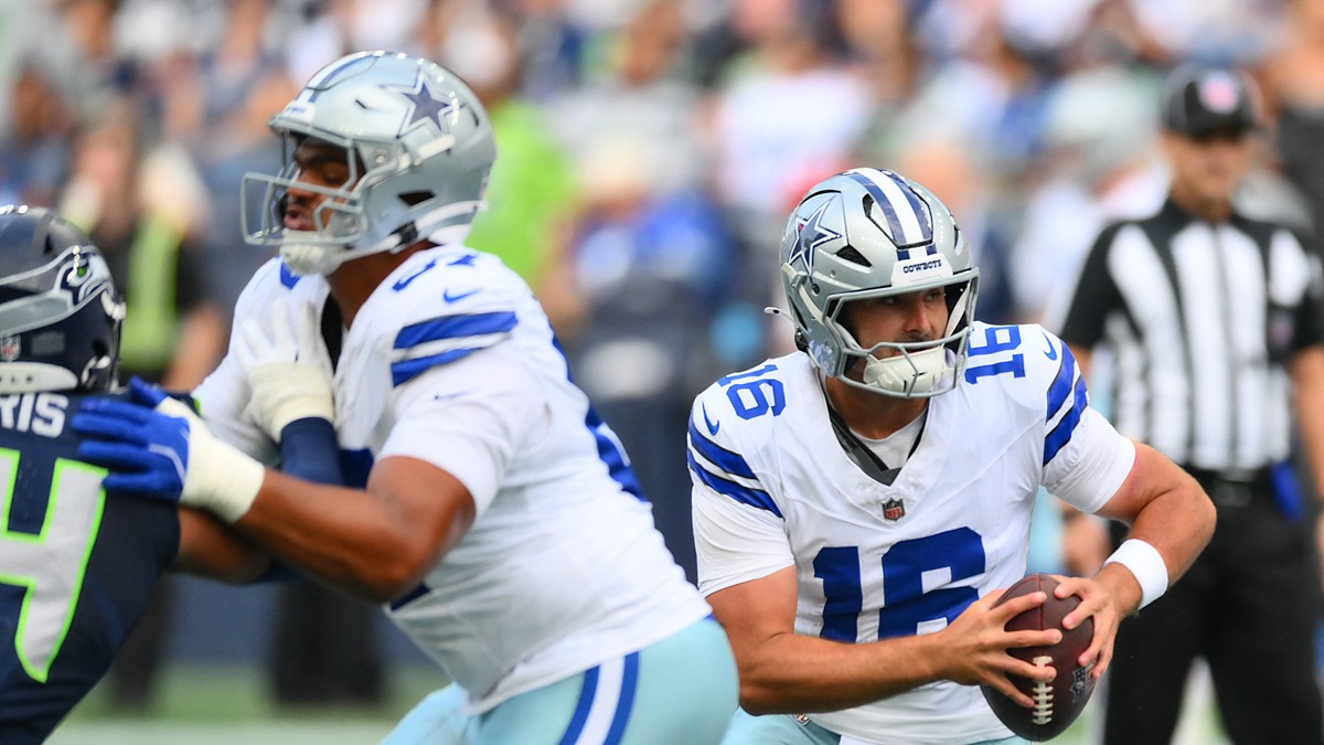 Dallas Cowboys quarterback Sam Howell holds the ball and scans downfield as a lineman blocks a Seattle Seahawks defender.
