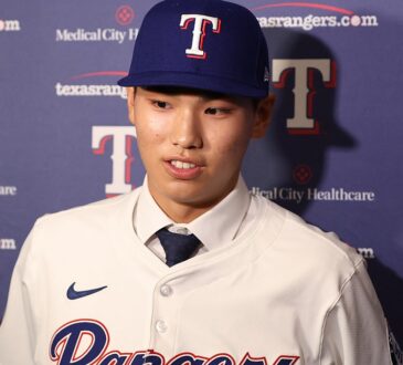 Texas Rangers two-way prospect Seong-Jun Kim speaks to reporters in a Rangers jersey and cap at Globe Life Field.