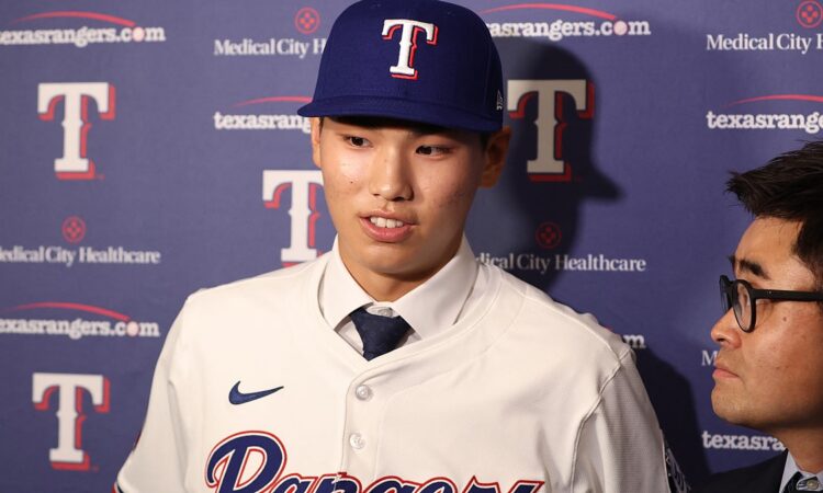 Texas Rangers two-way prospect Seong-Jun Kim speaks to reporters in a Rangers jersey and cap at Globe Life Field.
