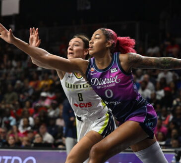 Washington Mystics center Shakira Austin and Dallas Wings forward Alanna Smith stretch for a loose ball.