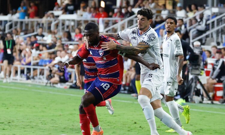 FC Dallas defender Shaq Moore holds off a Querétaro midfielder while dribbling along the touchline