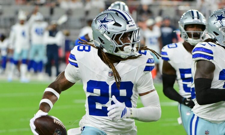 Dallas Cowboys cornerback Shavon Revel Jr. carries the ball upfield after an interception as teammates trail him.