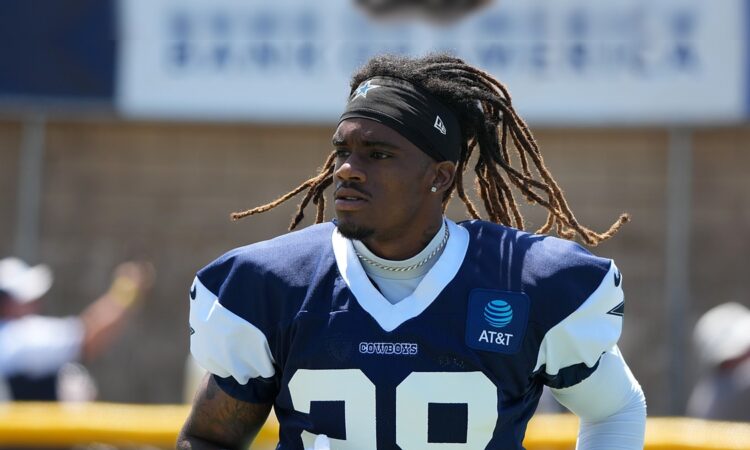 Dallas Cowboys cornerback Shavon Revel Jr. walks the practice field holding his gloves at training camp.