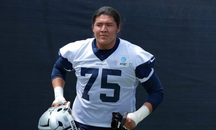 Dallas Cowboys offensive tackle Shiyazh Pete carries his helmet in a No. 75 practice jersey at training camp.